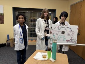 Students standing next to their science project smiling