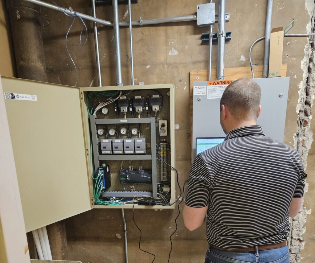 Man calibrating dufferent things in a panel with his tools and computer